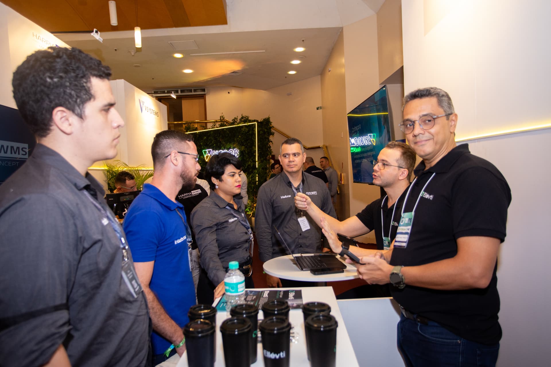 Participantes conversando com expositores na área de estandes