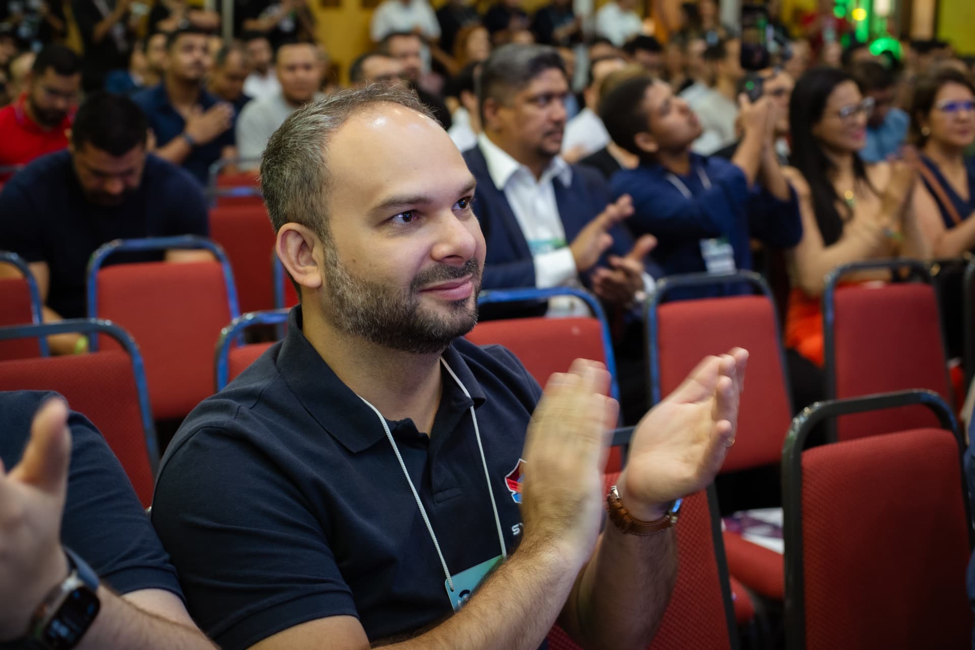 Participante aplaudindo durante palestra no auditório
